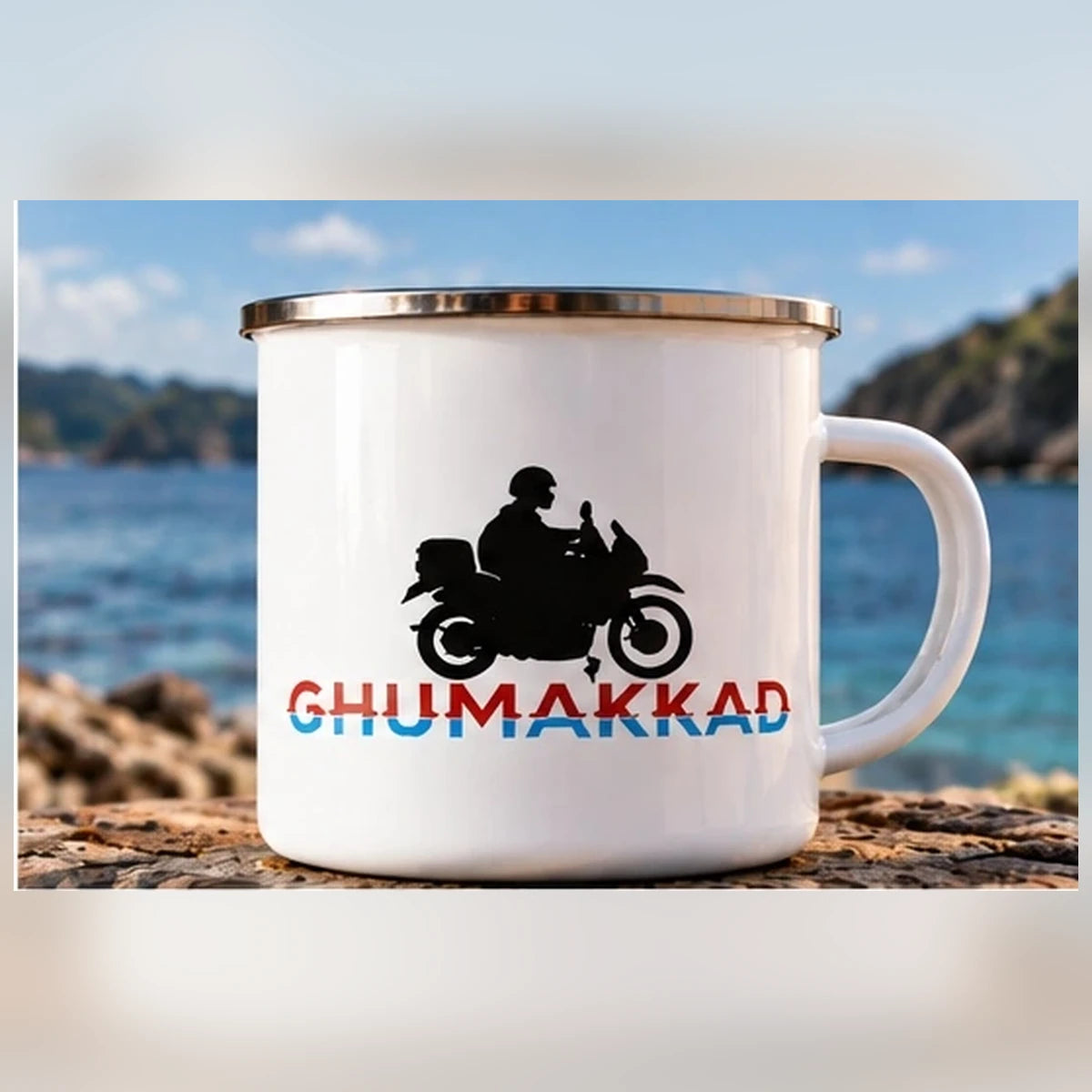 Front view of GHUMAKKAD white enamel motorcycle mug with double-sided biker design and ocean background
