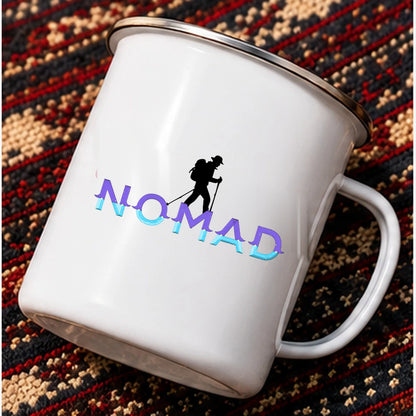 Nomad enamel mug tilted on patterned travel rug showing the original mountain hiker graphic and purple cyan letters