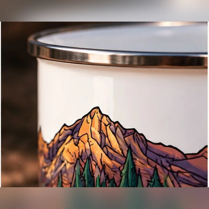 Close-up of enamel mug mountain artwork showing colourful peaks, pine trees and steel rim