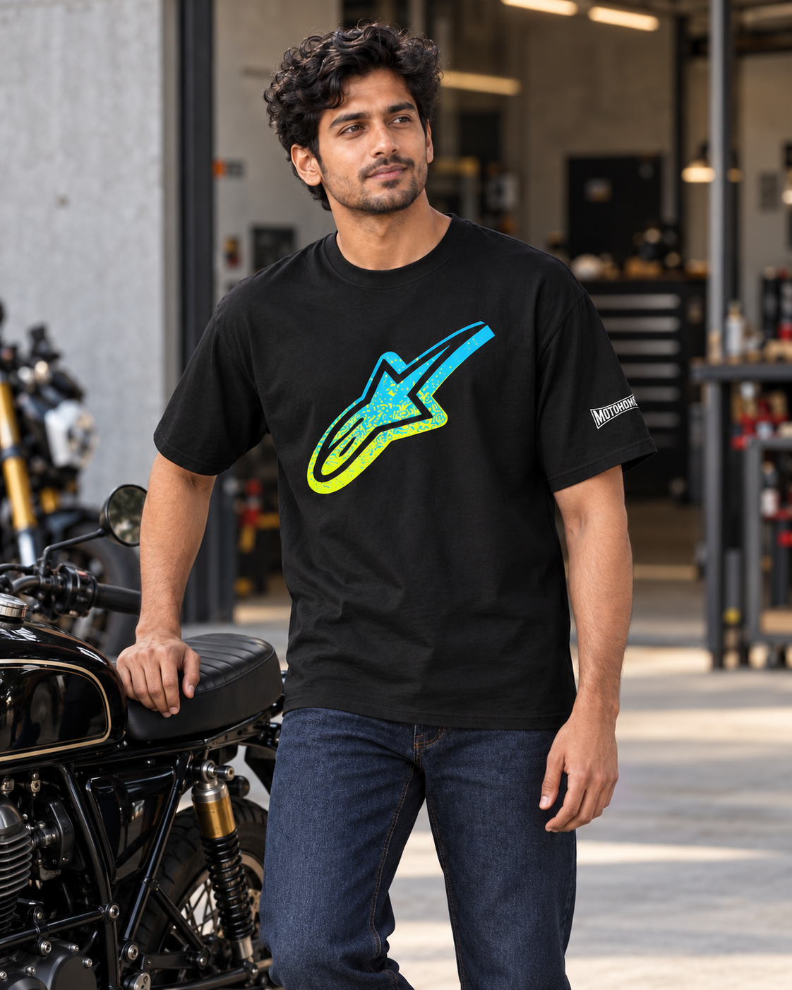 Black Alpinestars Astar oversized T-shirt styled with jeans beside a motorcycle