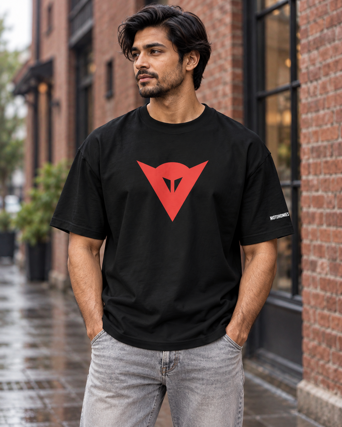 Front view of the black Dainese oversized T-shirt with red chest emblem and white Motohomies sleeve lettering