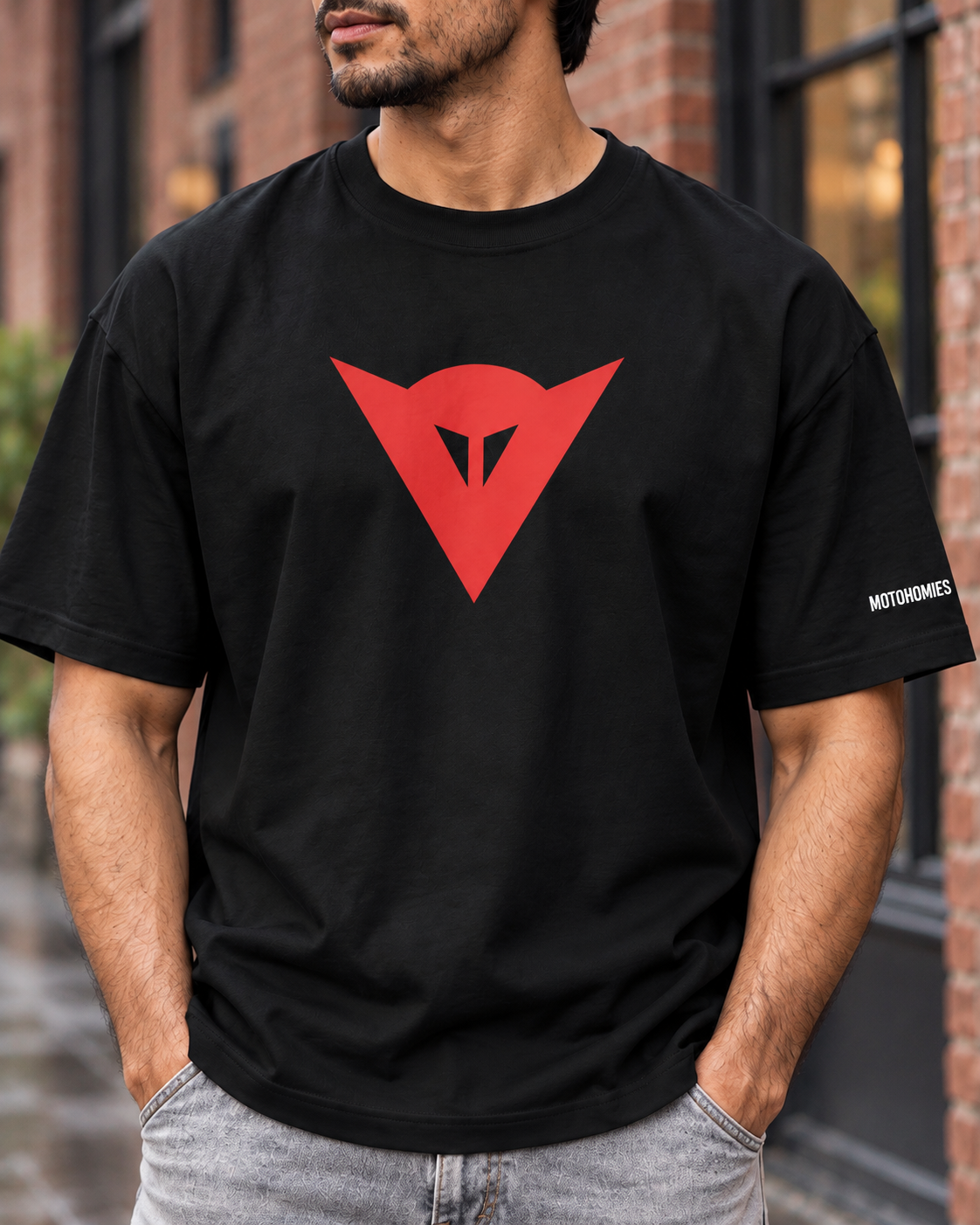 Close-up of the red Dainese chest emblem and border-free Motohomies sleeve lettering on black fabric