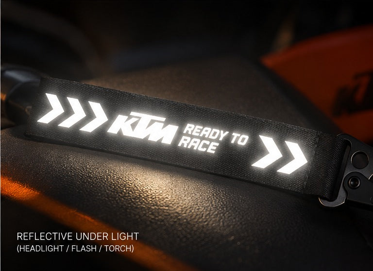KTM motorcycle keychain with reflective DTF white text shining under flashlight