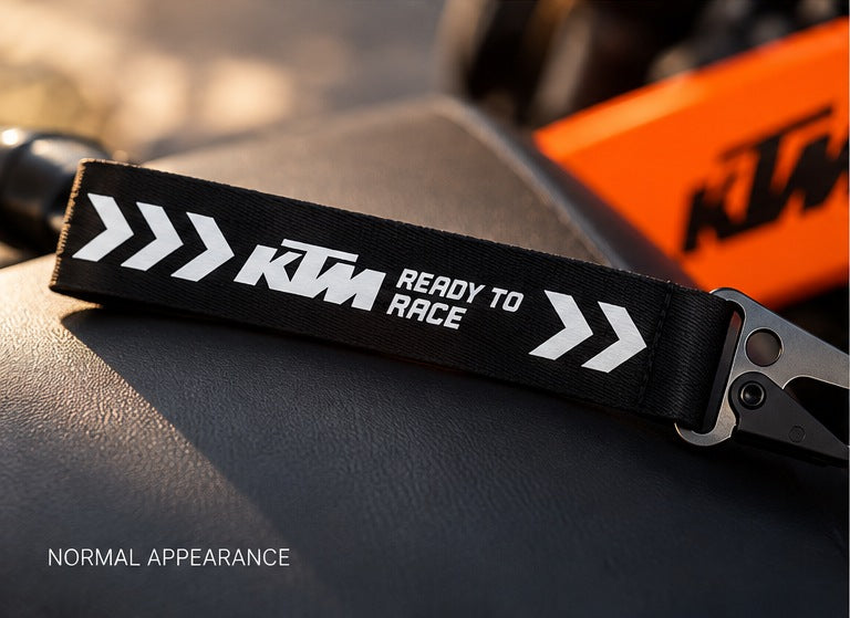 KTM Ready To Race woven keychain in normal light on motorcycle seat