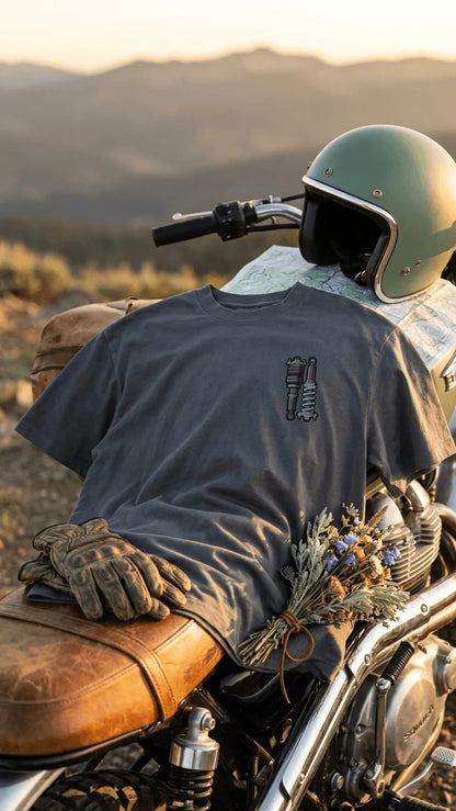 Stance Outlaws coilover tee on cafe racer motorcycle with vintage open-face helmet, leather gloves and map at sunset
