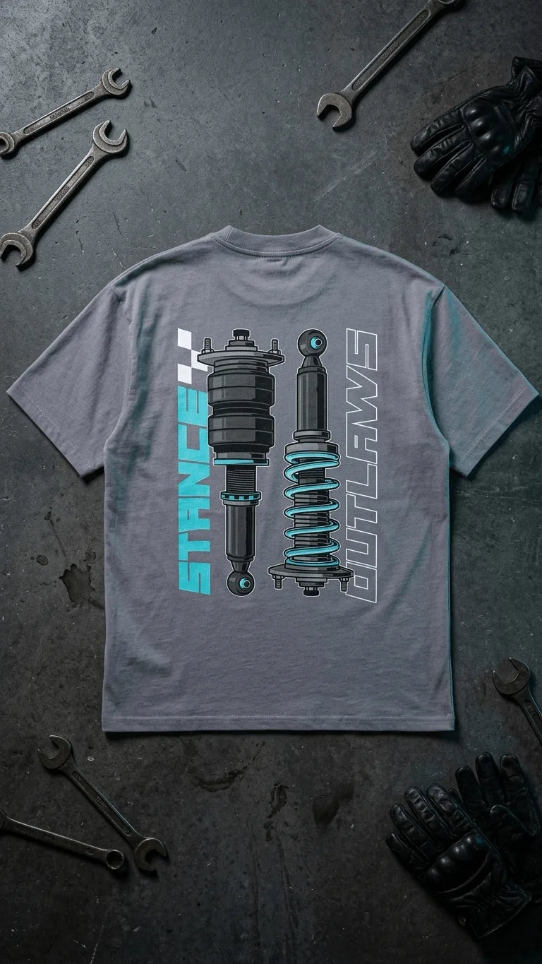 Stance Outlaws coilover tee flatlay grey product shot with brown leather riding gloves and wrench on garage floor