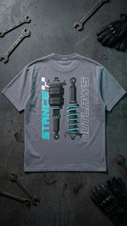 Stance Outlaws coilover tee flatlay grey product shot with brown leather riding gloves and wrench on garage floor