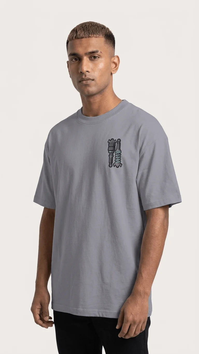 Indian male model wearing Stance Outlaws coilover tee front view with chest pocket suspension graphic in grey