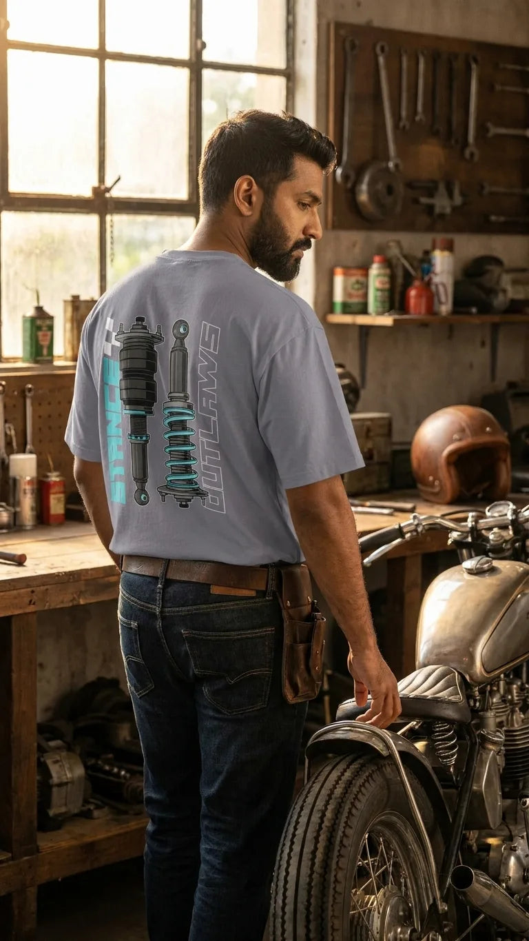 Bearded Indian rider in Stance Outlaws coilover tee inside vintage motorcycle workshop with classic bike and pegboard tools