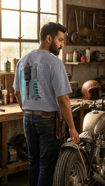 Bearded Indian rider in Stance Outlaws coilover tee inside vintage motorcycle workshop with classic bike and pegboard tools